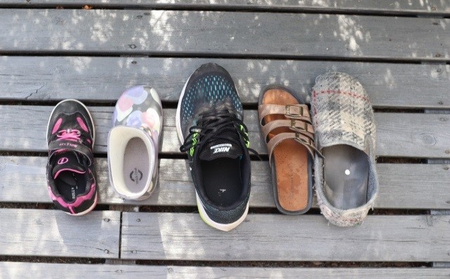Fem ulike sko fra barn til voksenstørrelse på terassegulv. Gulvet er av tre. Fotograf: Bente Iren Nyland.